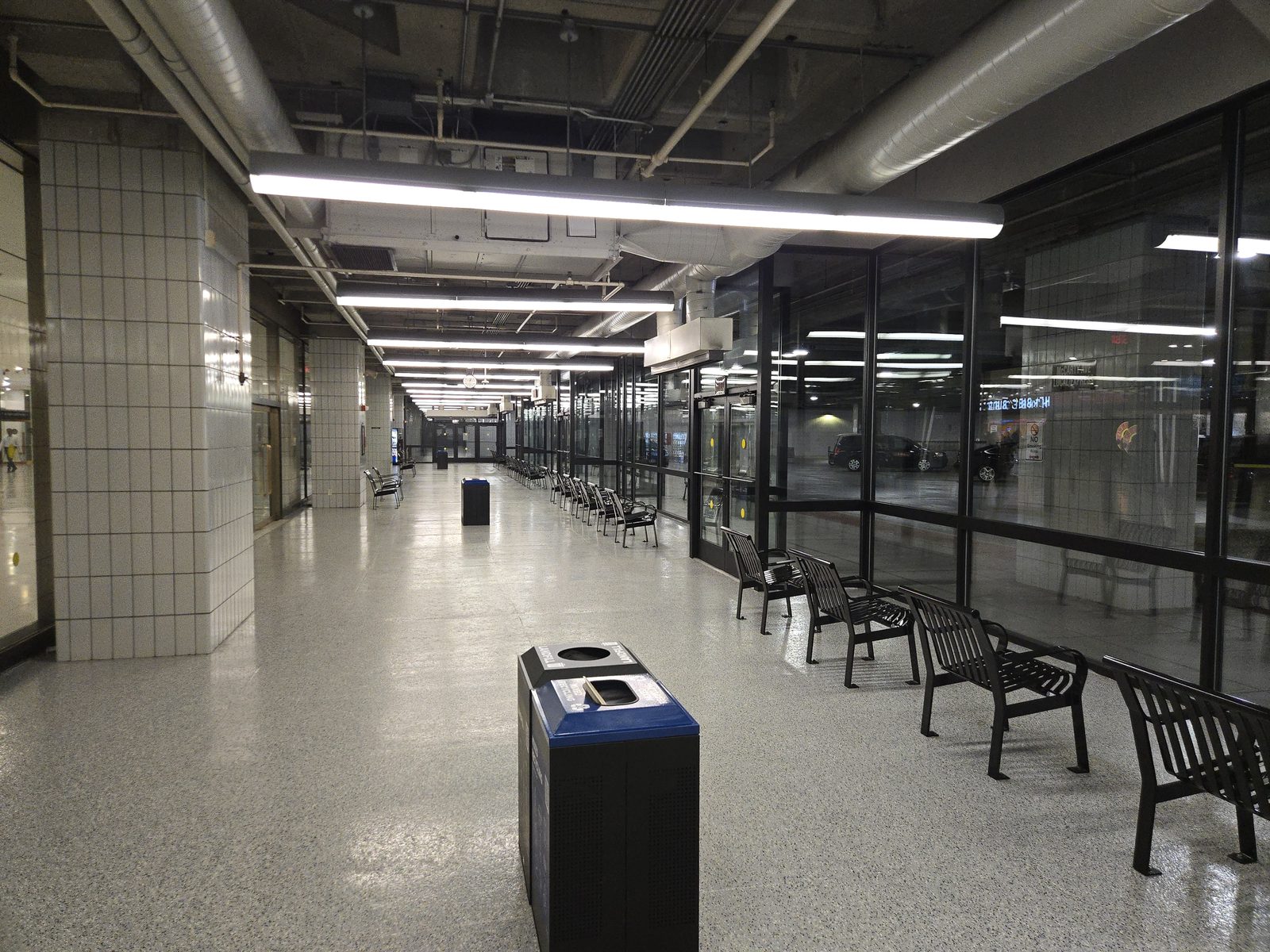 The Empire State Plaza Concourse waiting hall, with benches lined along a glass wall facing the enclosed bus deck.